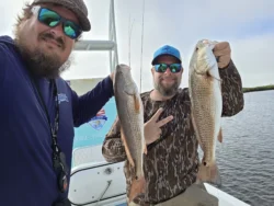 Captain Larry and a guest hold up their catches from a fishing charter.